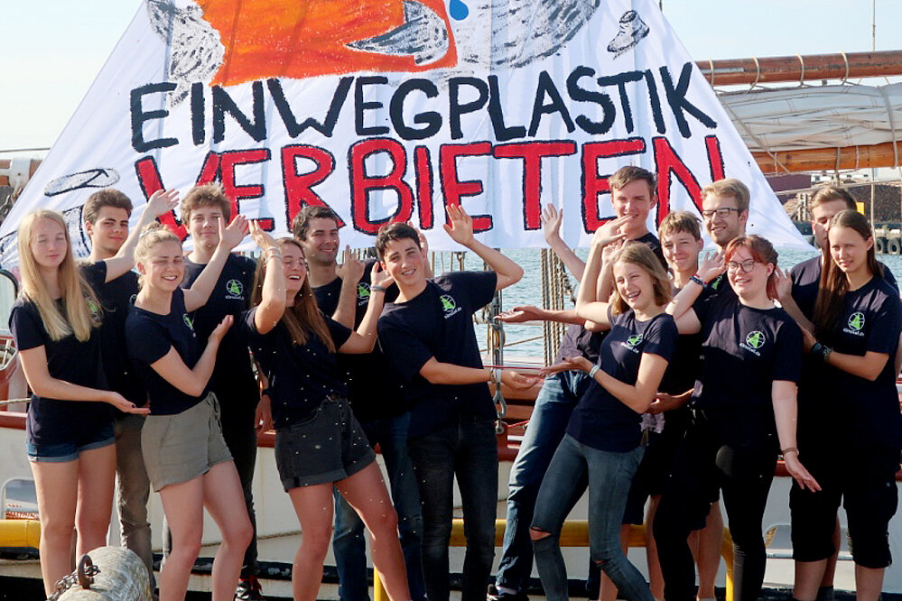 14 junge Menschen vor einem Banner mit der Aufschrift: Einwegplastik verbieten.